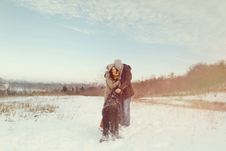 Couple with their dog enjoying the first snowfall, symbolizing the start of snow day season in the U.S.