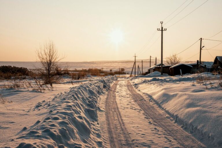 Snow-covered rural road at sunrise with icy tracks, symbolizing school safety concerns when roads are hazardous.