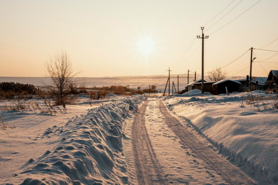 Snow-covered rural road at sunrise with icy tracks, symbolizing school safety concerns when roads are hazardous.