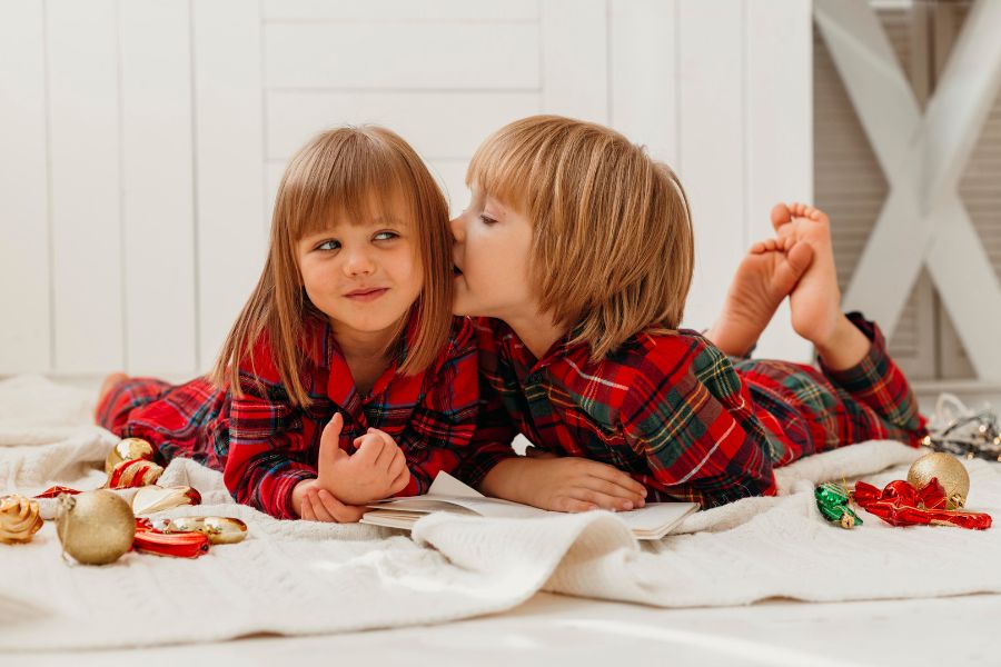 Two children whispering secrets while wearing plaid pajamas, symbolizing the playful theme of a snow day probability quiz.